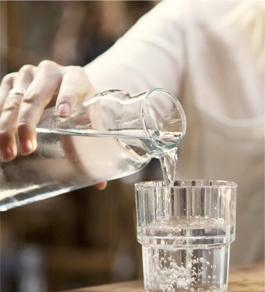 mano vertiendo agua limpia en un vaso