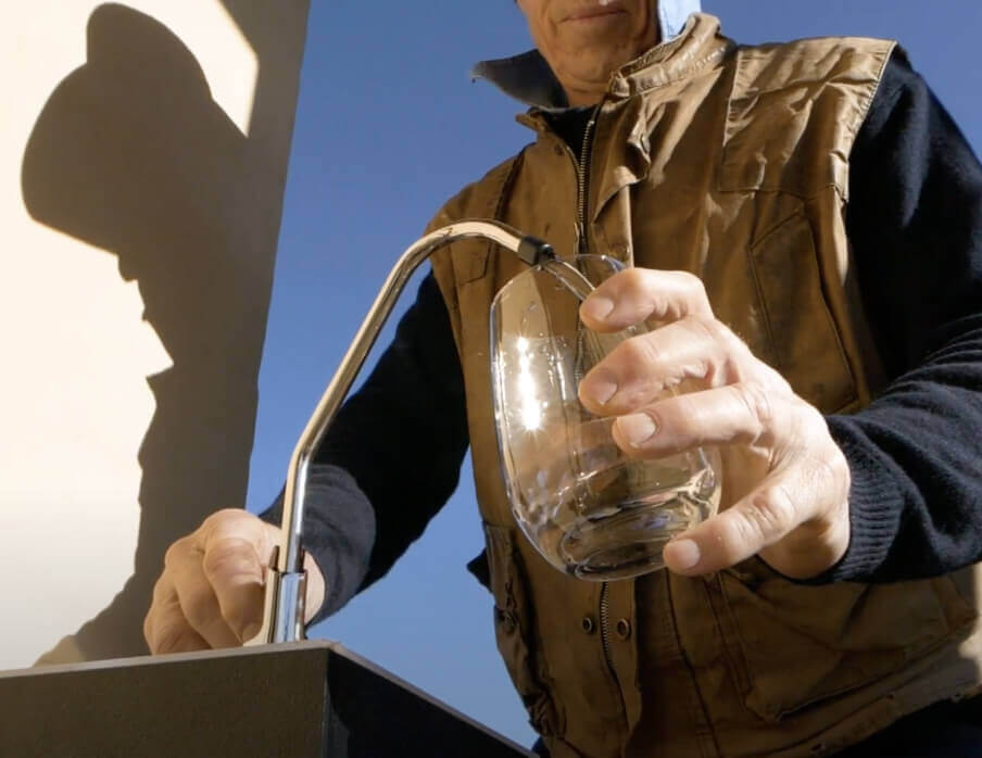 Hombre llenando el vaso con agua potable limpia de la estación de recarga de agua source meta 3