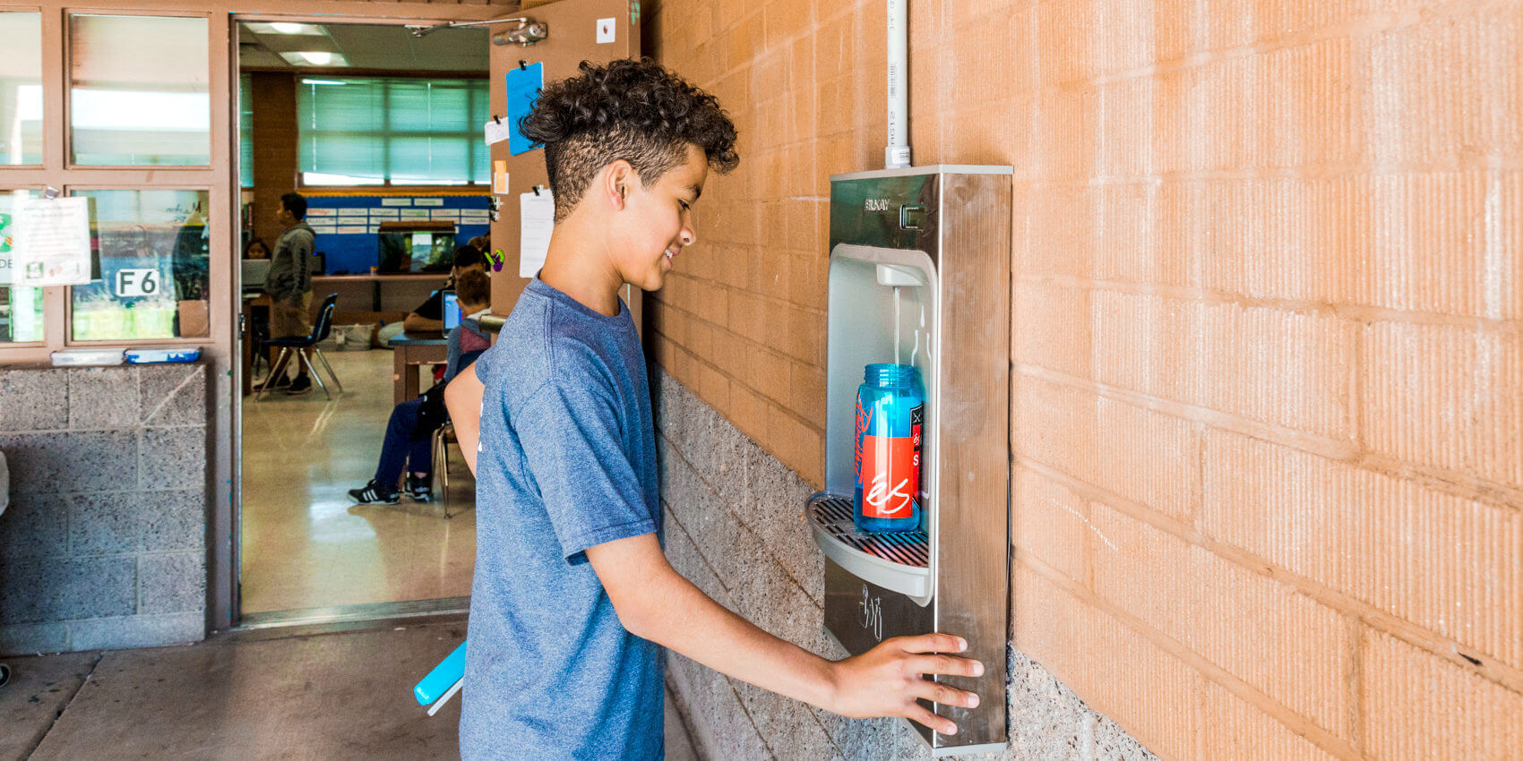 Boy filling water container at SOURCE dispenser